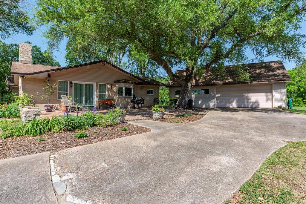 Enjoy the shaded patio framed by mature landscaping and a sprawling tree that offers natural cover and charm. Just steps away is the oversized 4-car garage, equipped with an A/C window unit and available plumbing-perfect for a workshop studio or future guest suite.