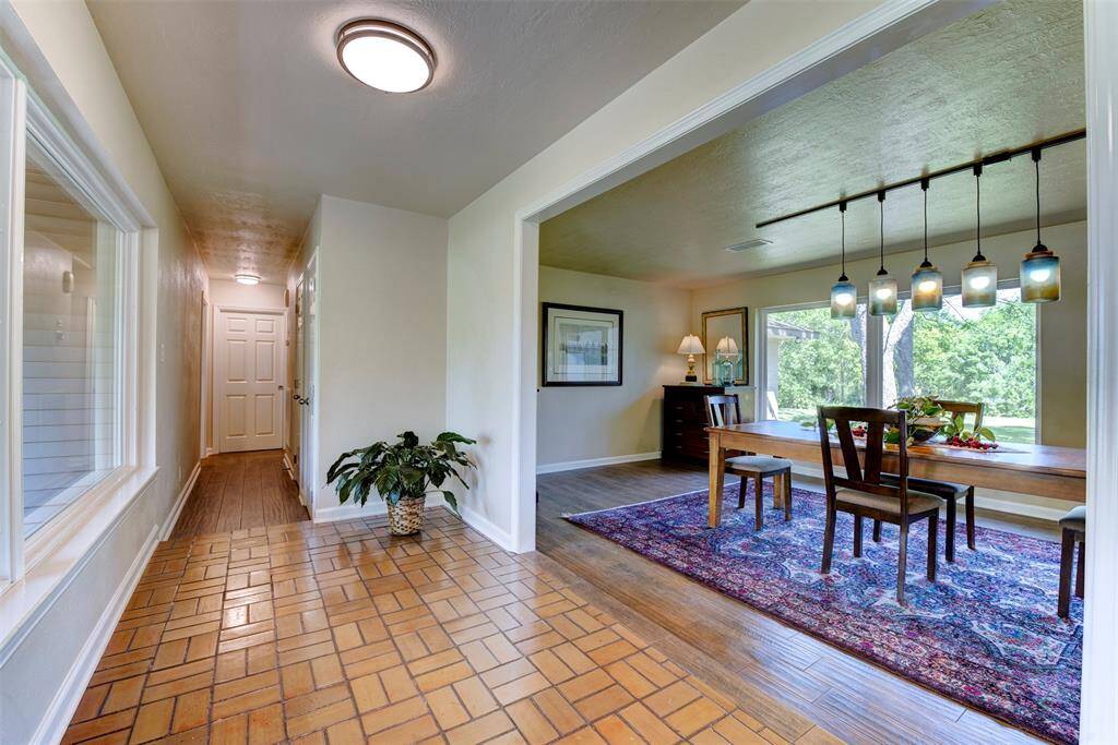 Inviting foyer with classic tile flooring opens to a bright dining area featuring large picture windows, updated lighting and rich wood looking tile flooring. A great flow for hosting and everyday living.
