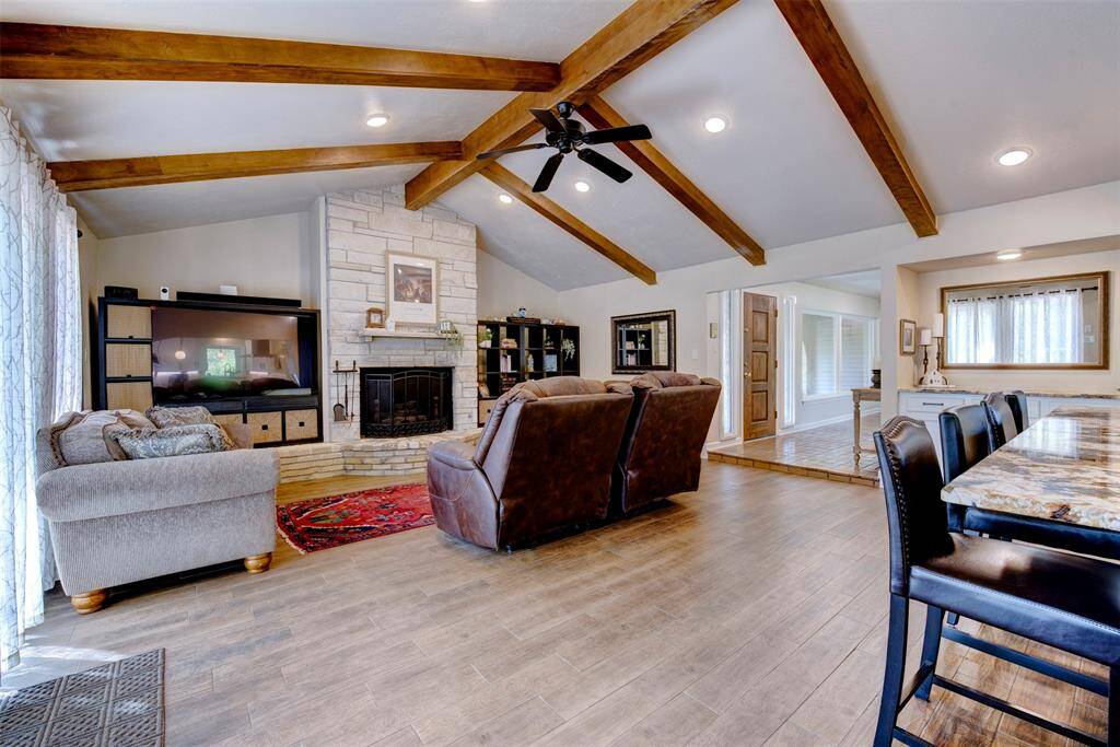 The den features dramatic exposed wood beams. The warm looking flooring elevates the ambiance making a perfect place for relaxing.