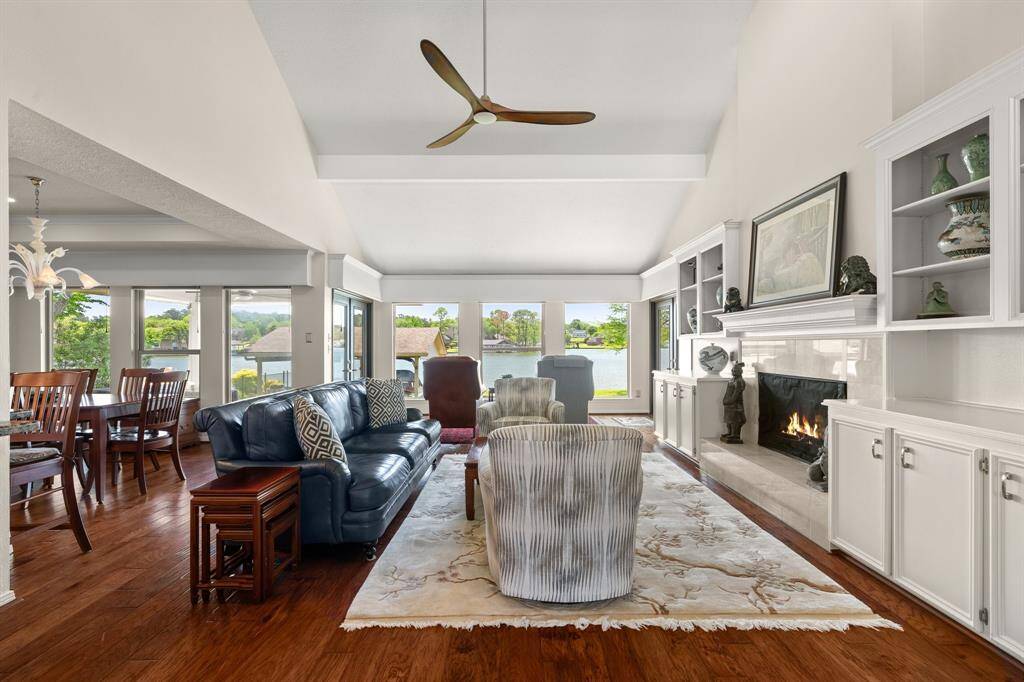 The living room features high ceilings, bookshelves and cabinets for storage and open to the dining and kitchen areas.