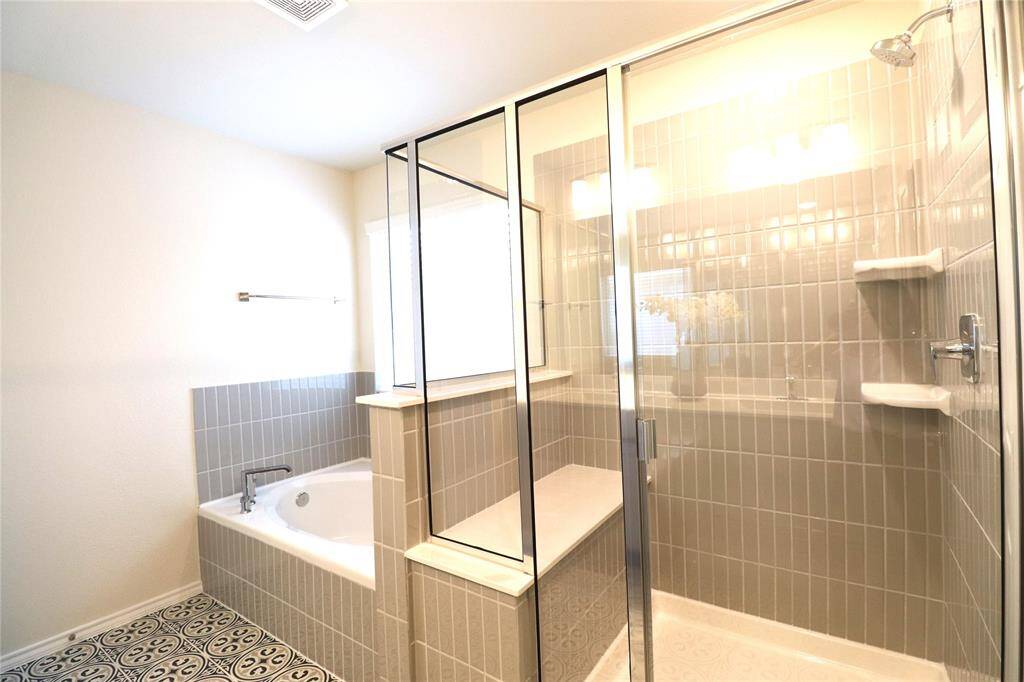This bathroom features a spacious glass-enclosed shower with built-in shelving and a separate soaking tub.