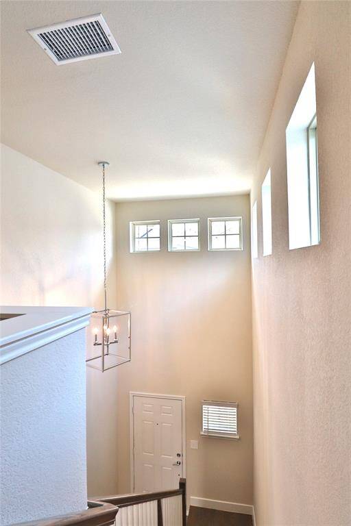 Bright, airy entryway with high ceilings, multiple windows for natural light, and a modern hanging light fixture.