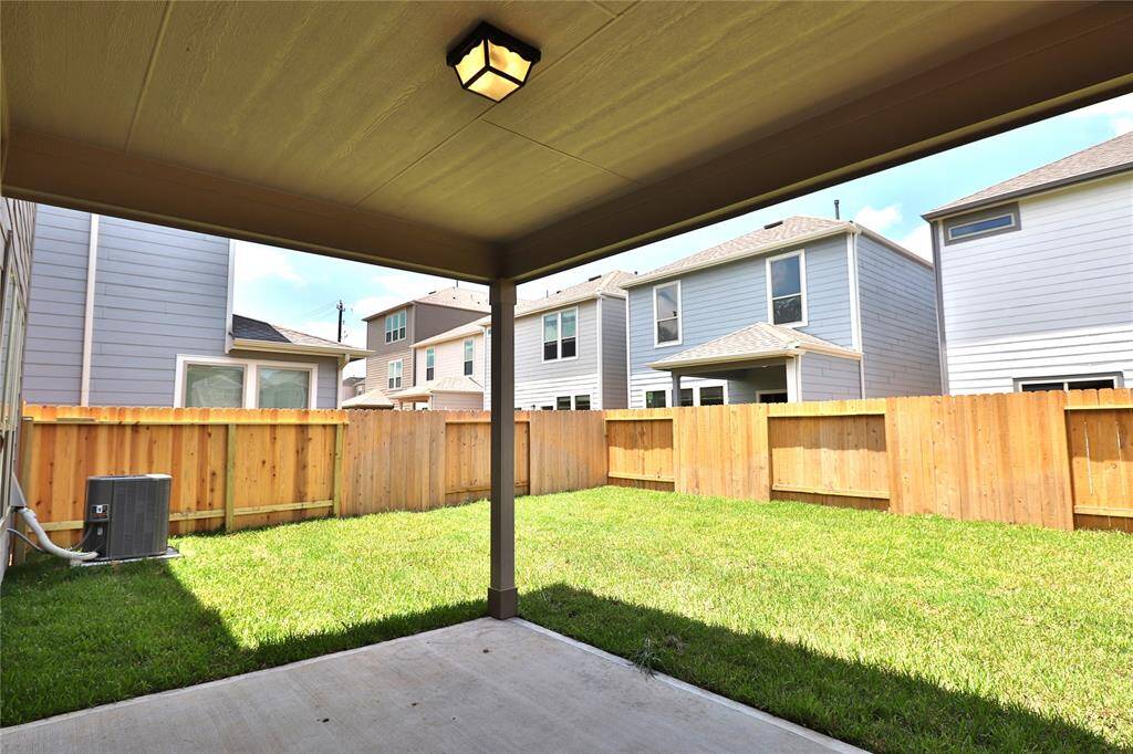 the backyard with a covered patio, spacious lawn, and wooden fence for privacy.