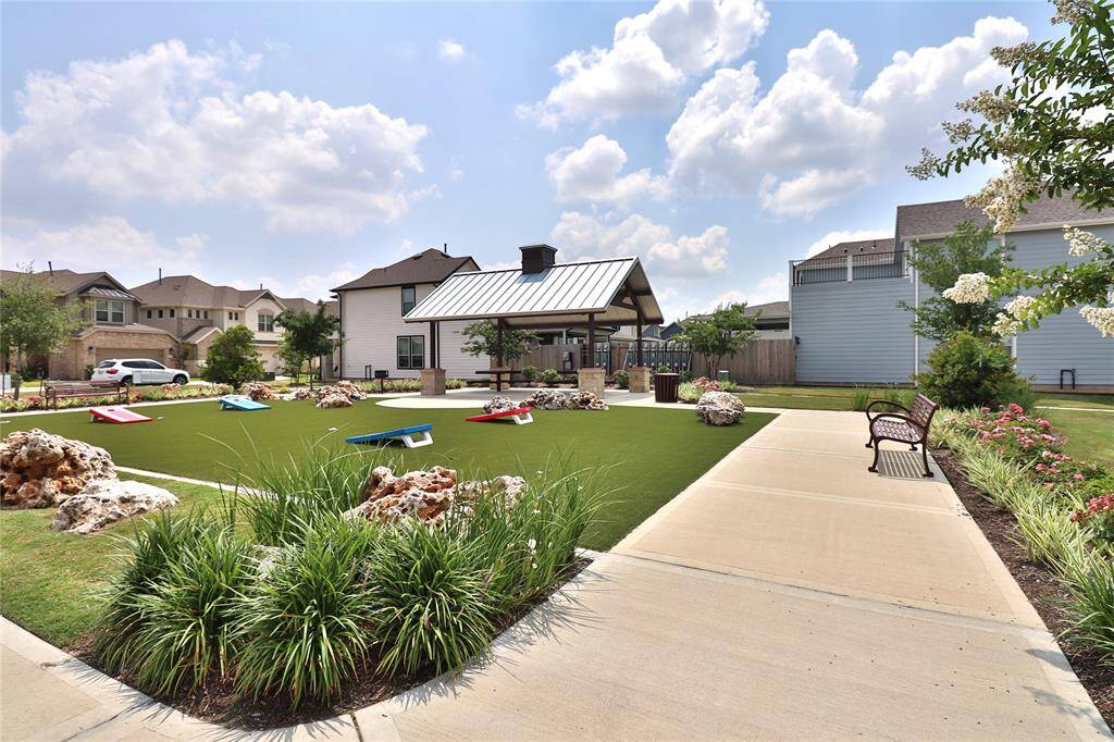 This photo shows a well-maintained community area featuring a covered pavilion, a manicured lawn .