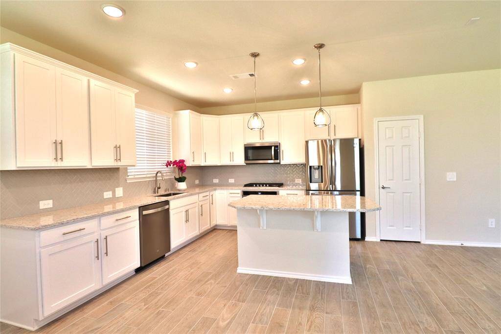 This home features recessed lighting, wood-look flooring, and ample counter space, creating an inviting and functional cooking area.