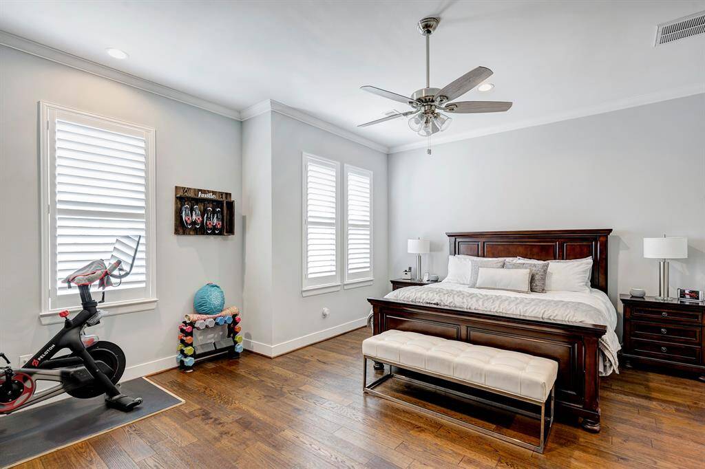 Primary bedroom features hardwood floors, crown moldings, abundant light and space for exercise equipment or seating area.
