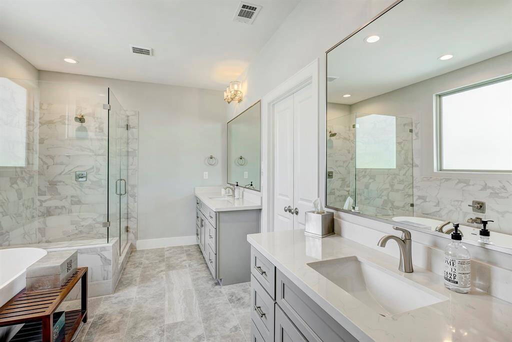 Spa like primary bath with free standing soaking tub, walk-in shower with glass enclosure, 2 separate sink areas and 2 walk-in closets.