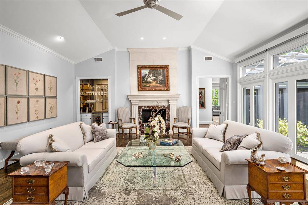 Formal living room includes a wet bar, high ceiling and stone mantle gas fireplace with marble surround.
