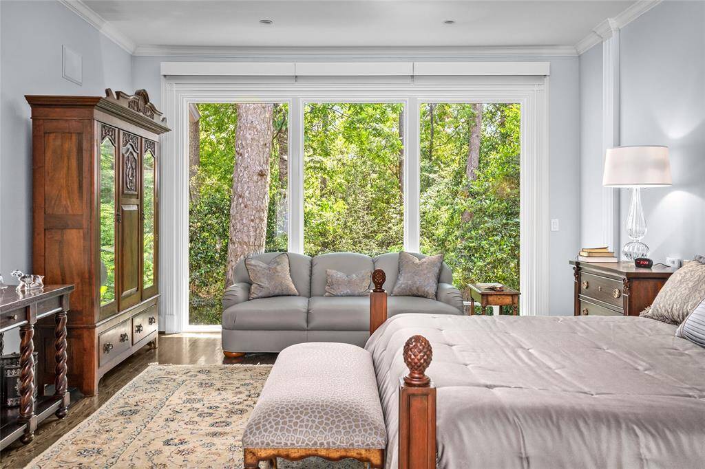 Breathtaking primary suite with a view of lush foliage. The primary suite also includes motorized hurricane shutters.