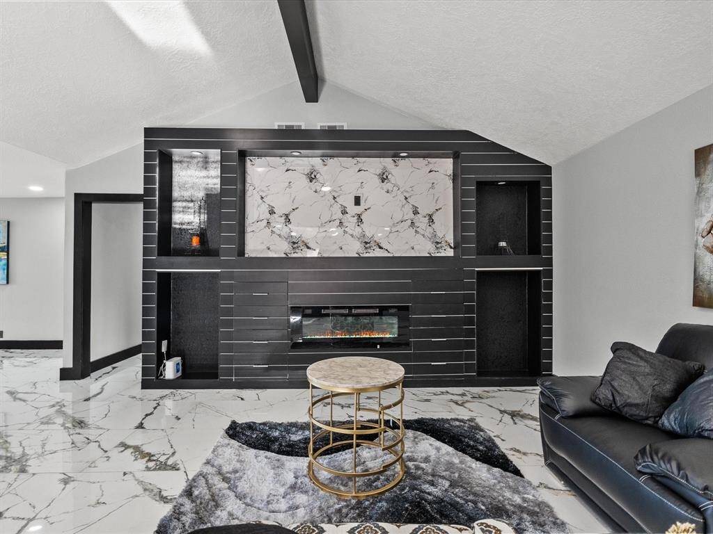 The custom entertainment center w/built ins accents a den/kitchen combo creating an inviting and luxurious atmosphere