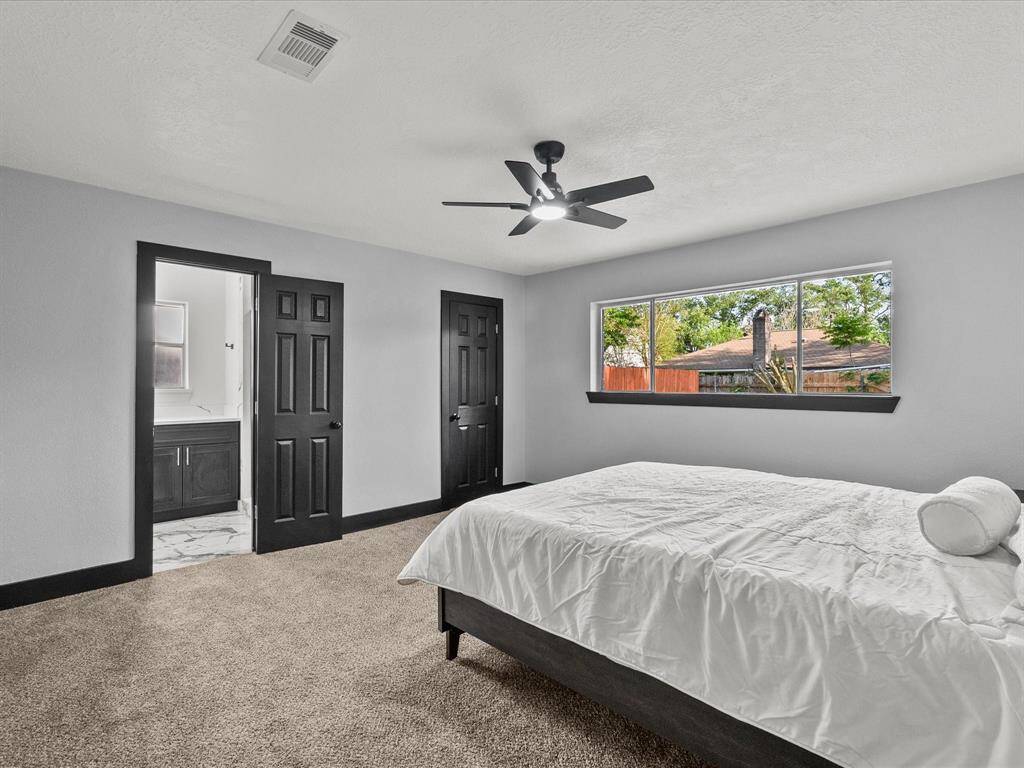 The primary bedroom is spacious with neutral tones, large windows, a ceiling fan, and an ensuite bathroom.