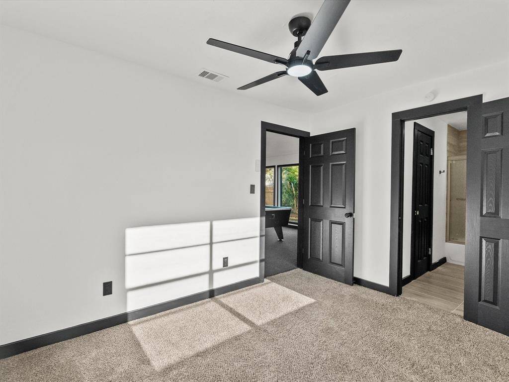 This bed- room is bright and spacious with neutral carpeting and a ceiling fan. It connects to a bathroom and the adjacent game room