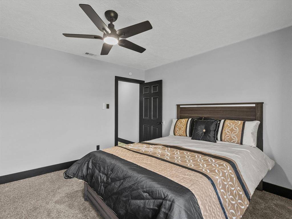 This bedroom features a neutral palette with light walls and dark trim, complemented by a modern ceiling fan.