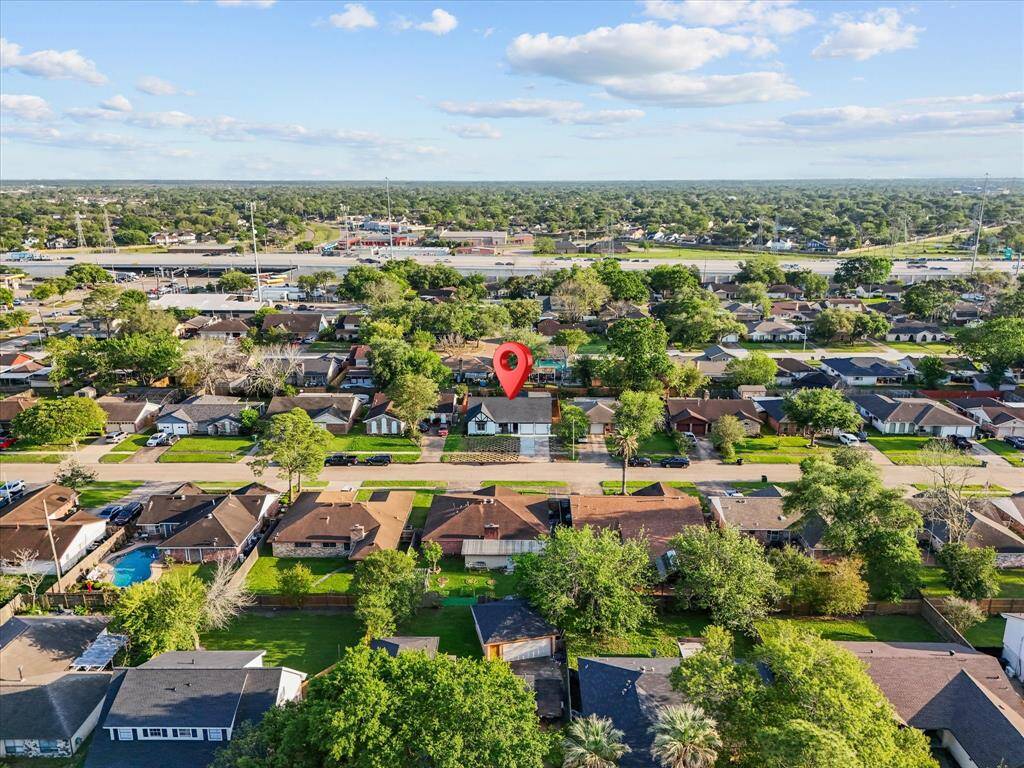 This aerial photo showcases a suburban neighborhood with single-family homes, lush greenery, and tree-lined streets. The area appears well-maintained and spacious, offering a peaceful residential atmosphere.