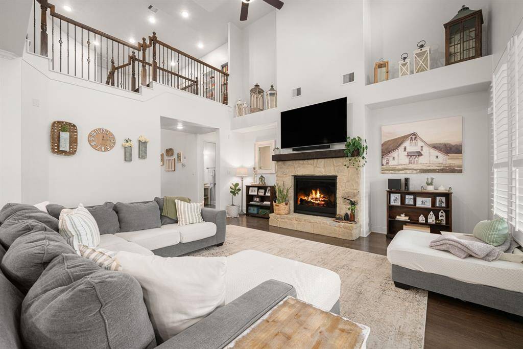 This stunning living area features soaring ceilings, gas log fireplace, niche cutouts for artwork or shelving, and plantation shutters.