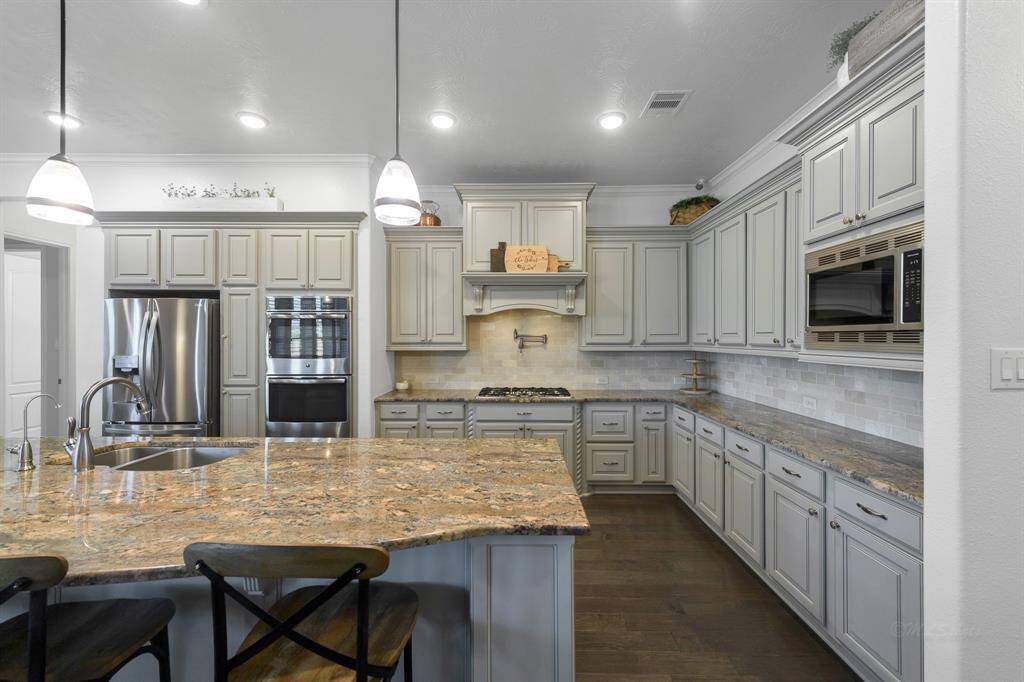 This is a dream kitchen! Gorgeous cabinetry, gas cooktop, stainless steel appliances, granite countertops, massive custom cut granite island, double ovens, pendant lighting, hardwood floors, and a pot filler!