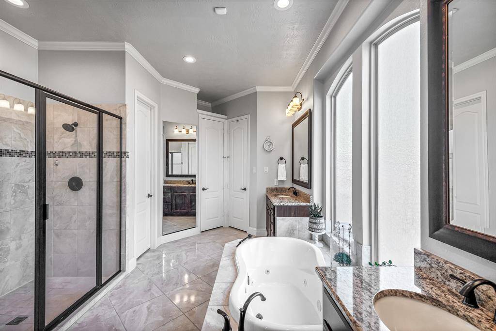 Come home to your own personal spa and relax at the end of each day. This primary ensuite is pure luxury with separate vanities, granite countertops, tile floors, large glass-enclosed shower with two shower heads, jetted tub, large windows for lots of natural light, two walk-in closets, crown molding, and recessed lighting.