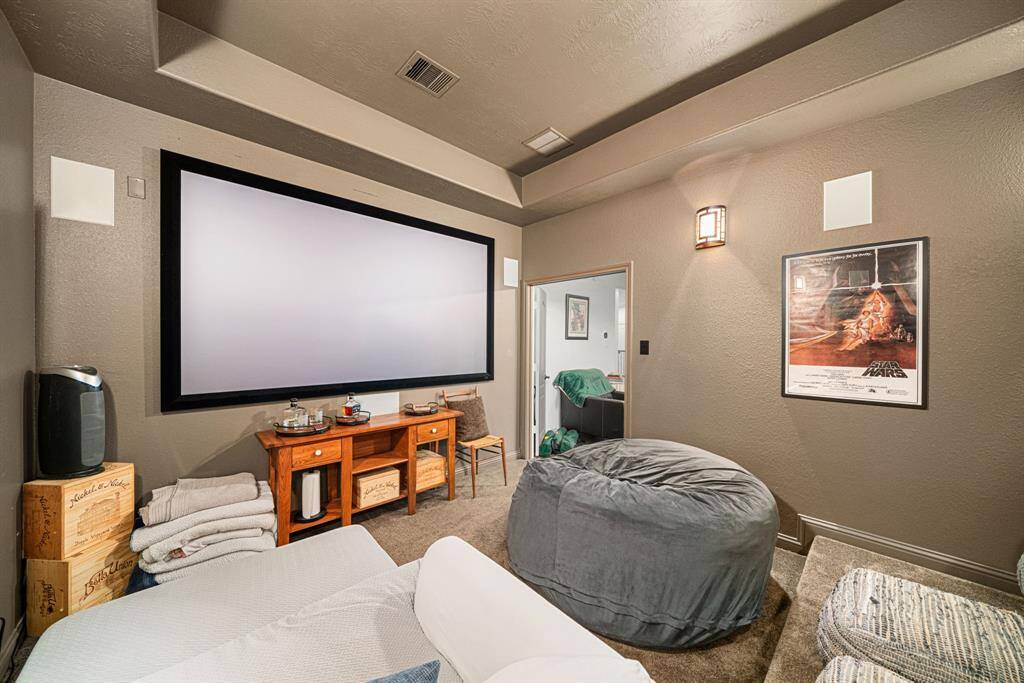 This dedicated media room features a tray ceiling, built-in speakers, theater lighting, double doors, and tiered flooring. Get ready to pop the popcorn!