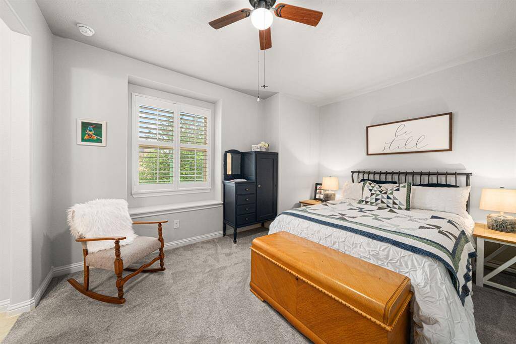 This upstairs bedroom is beautifully done with neutral paint and carpet, plantation shutters, walk-in closet, and ceiling fan. This space feels practically brand new, and shares a Hollywood bathroom with the other second floor bedroom.