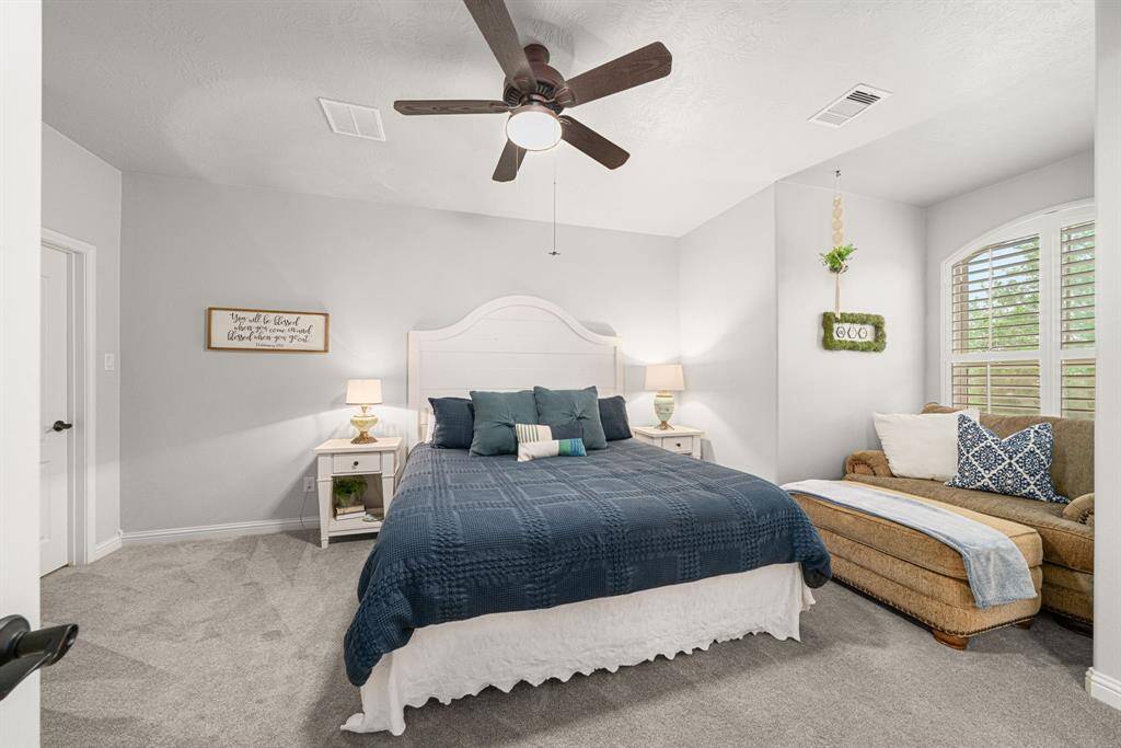 This upstairs bedroom is peaceful and beautifully appointed with neutral paint and carpet, plantation shutters, ceiling fan, and walk-in closet.