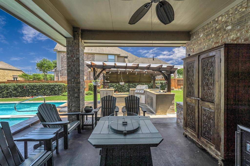 Step outside to this gorgeous outdoor oasis! This is just one of the many seating areas! Relax around the fire pit to watch TV, while grilling for your guests in the outdoor kitchen, and then afterwards take a dip into the pool and relax!