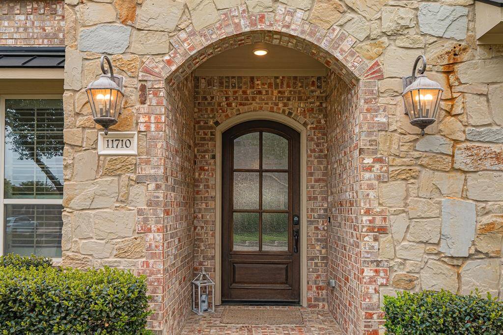 Arched brick, elegant carriage lighting, and a hardwood door with etched glass make this an absolutely unforgettable entryway.