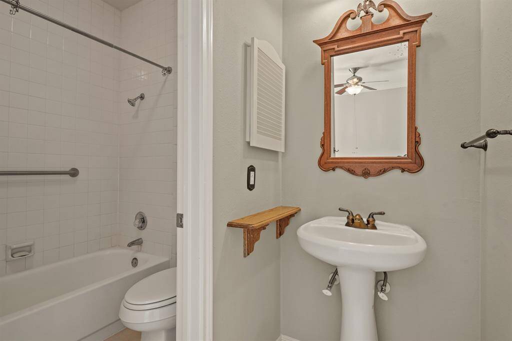 The secondary en-suite bathroom has a modern pedestal sink and tub/shower combo with tile surround.