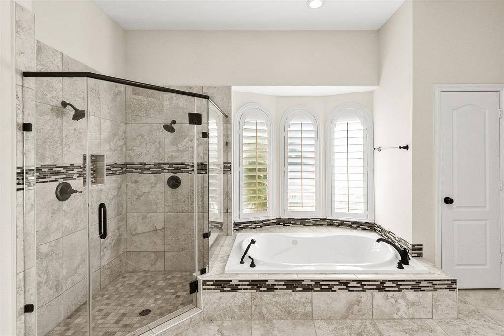 This beautiful Primary Bathroom features a gorgeous tiled walk-in shower, a large garden tub, and updated recessed lighting.