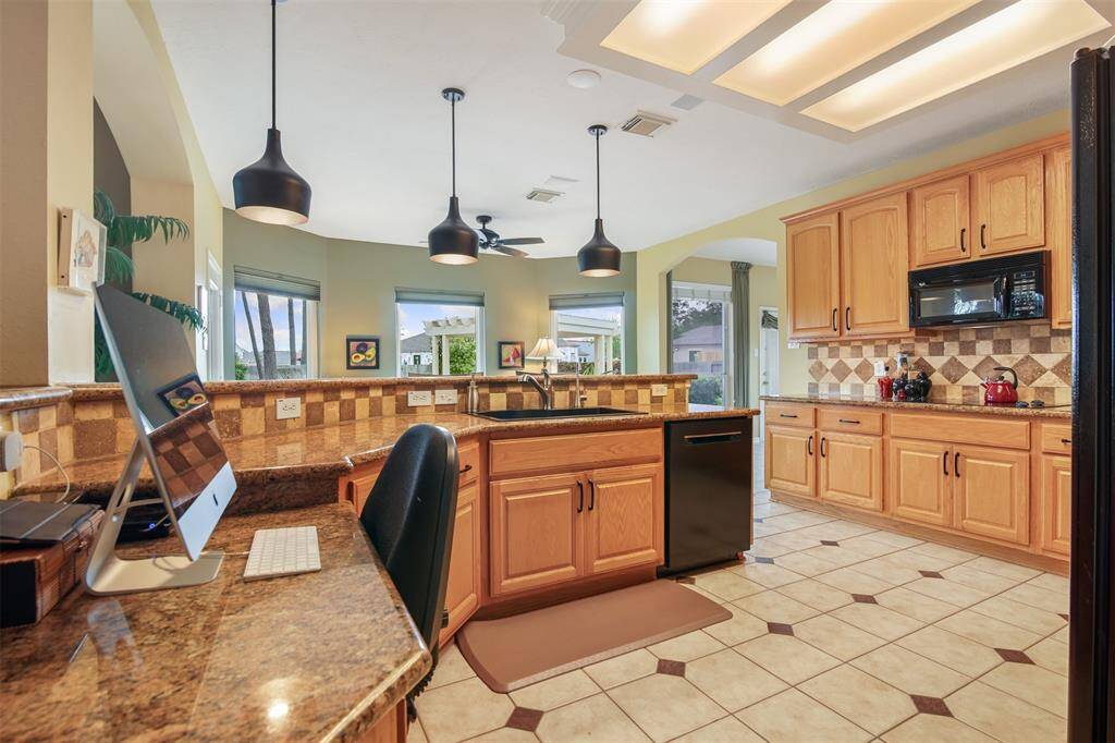 Another view of kitchen showing close up of countertop, breakfast bar with custom pendant lighting, and microwave.