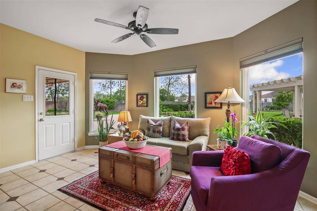 The breakfast room features tile flooring, large picture windows with shades and ceiling fan. It can also be used as an additional sitting room as seen here.