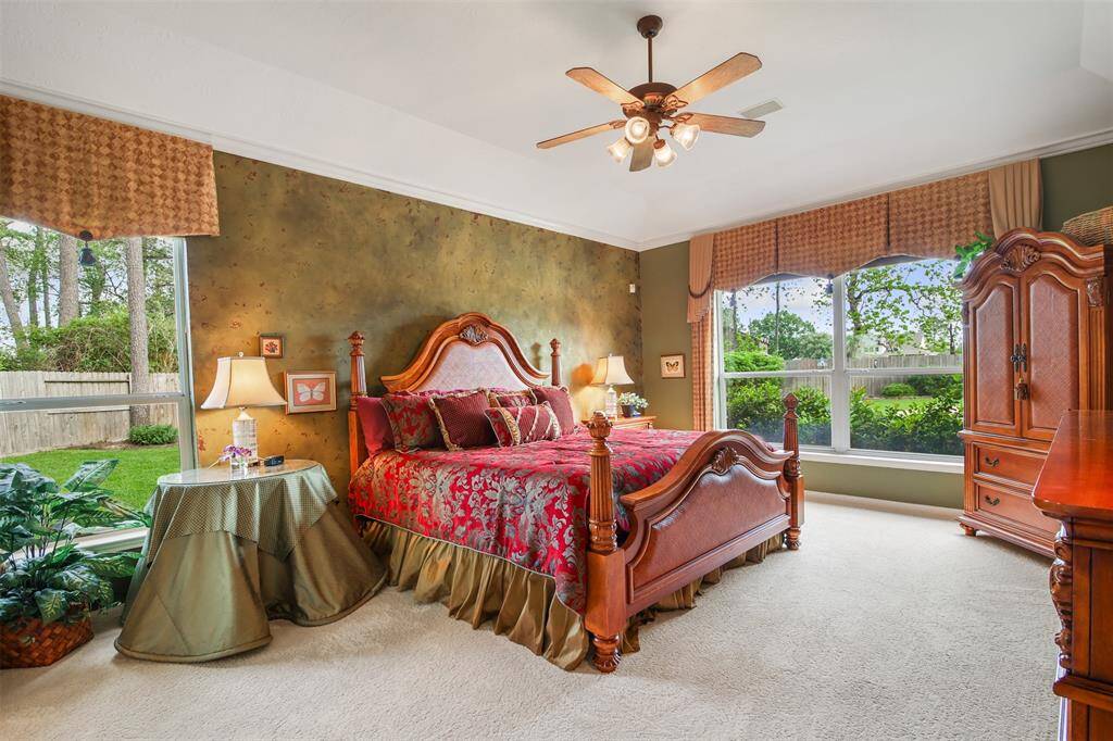 The primary bedroom is spacious with carpet, ceiling fan, crown molding and lots of windows for plenty of natural light. Custom faux painting accent wall.