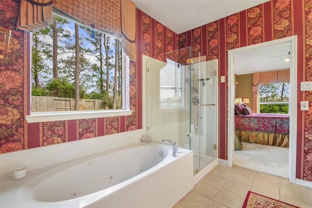 Primary bathroom has a frameless walk-in shower with separate jetted soaking tub.