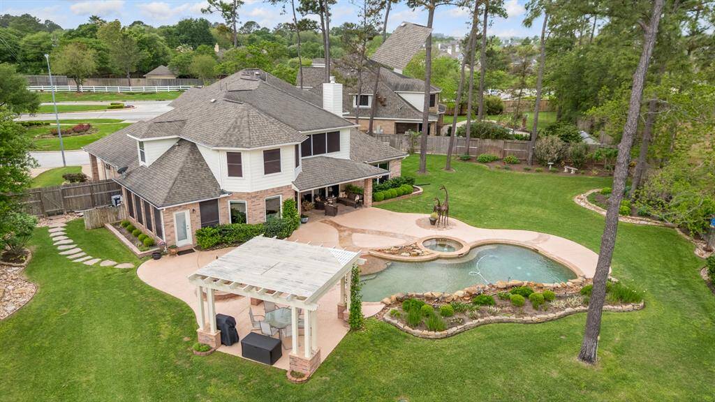 Aerial view of the backyard oasis with pool, covered patio area and lots of green space.