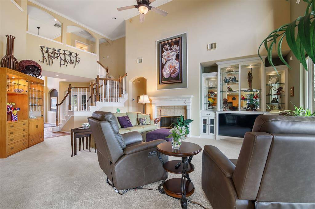 The family room features carpet, fireplace with tile surround and built ins with lit glass shelving.