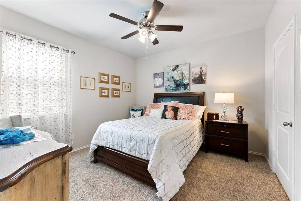 This spacious secondary bedroom features a ceiling fan for comfort, soft carpet underfoot, and walls painted in a neutral hue