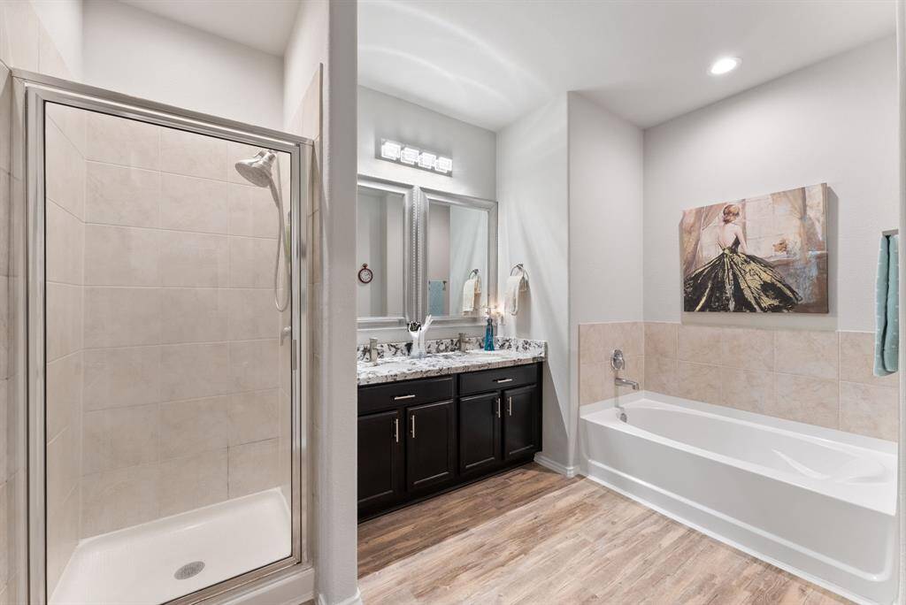 This expansive primary bathroom features a soaking tub, dual vanities, and a spacious walk-in shower