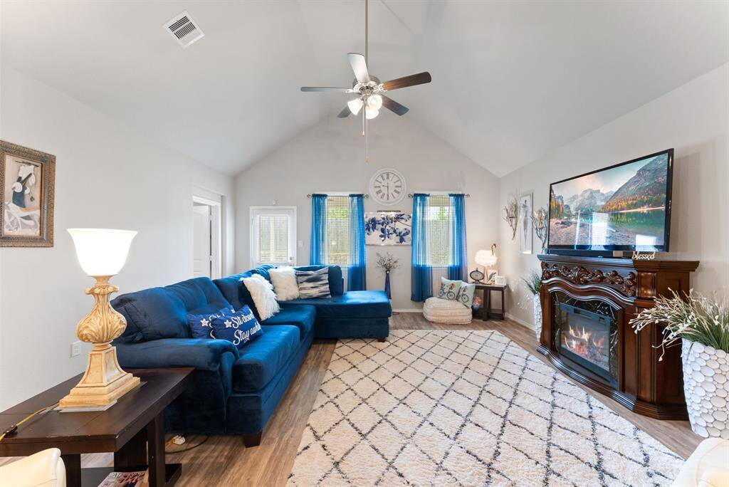The expansive living room features tall ceilings and a freestanding electric fireplace, creating a warm and inviting ambiance