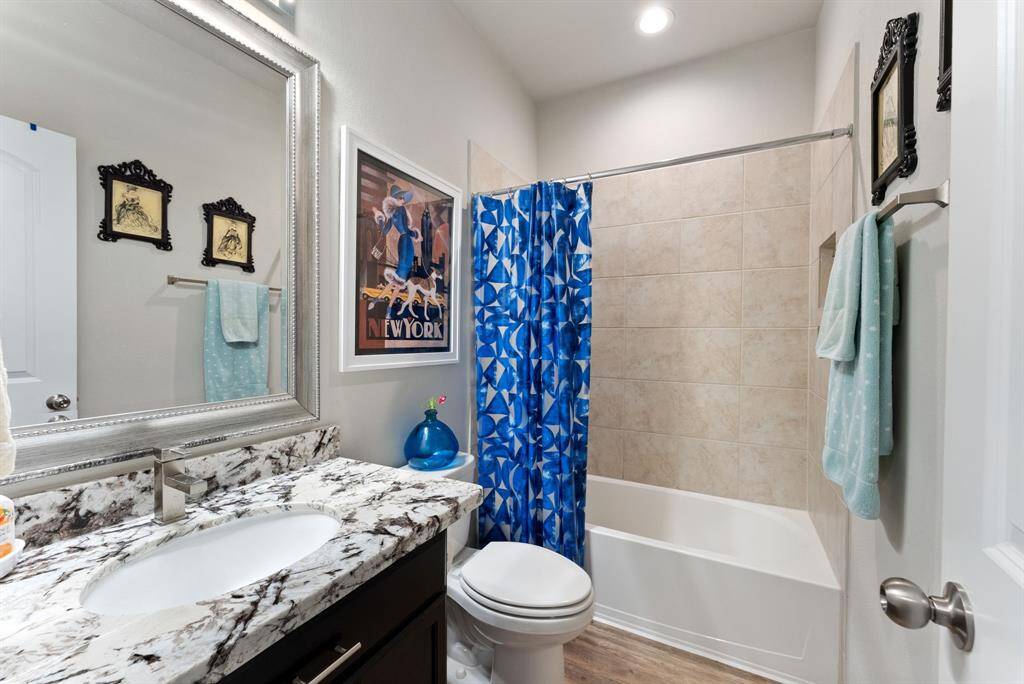 This full bathroom features granite counter tops and a tub and shower combo