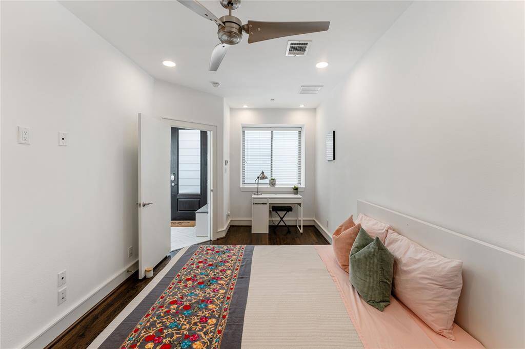The spacious secondary bedroom in the first floor features hardwood floors, a modern ceiling fan, recessed lighting and an en-suite bathroom.