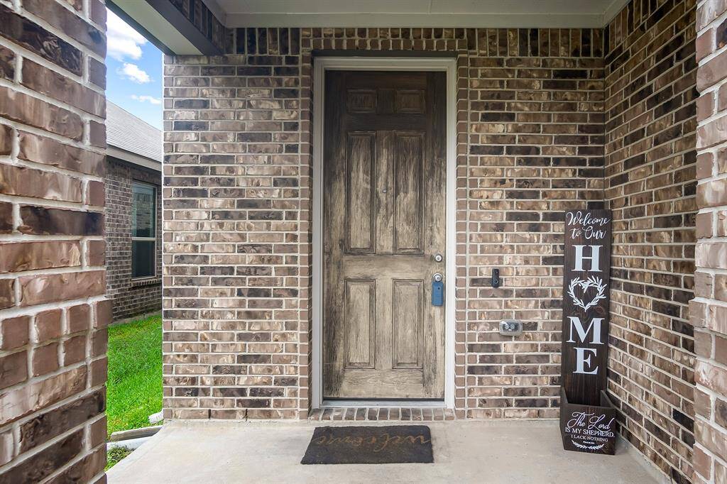 A welcoming front entrance with a rustic wooden door, set against a backdrop of classic brickwork. The area is well-lit and inviting.