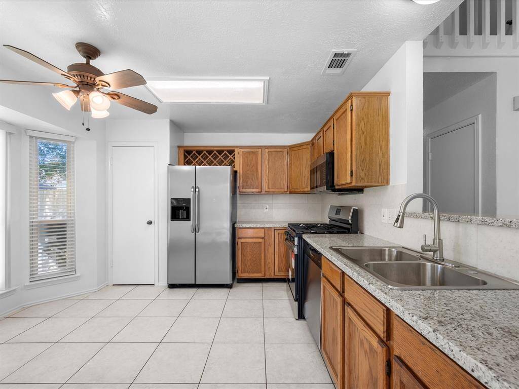 Breakfast area with large bay windows, tile flooring, and a ceiling fan, offering a cozy space with plenty of natural light and a view of the backyard.