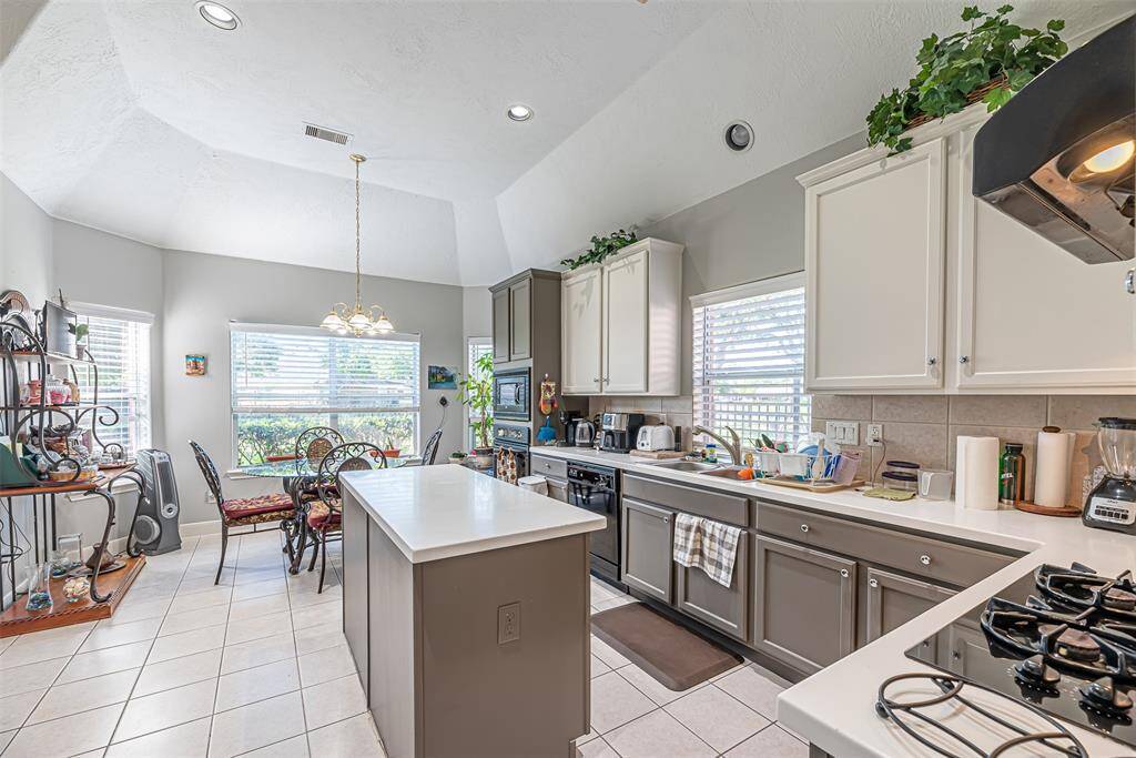 The kitchen has elevated ceilings, tile flooring and canned lighting.