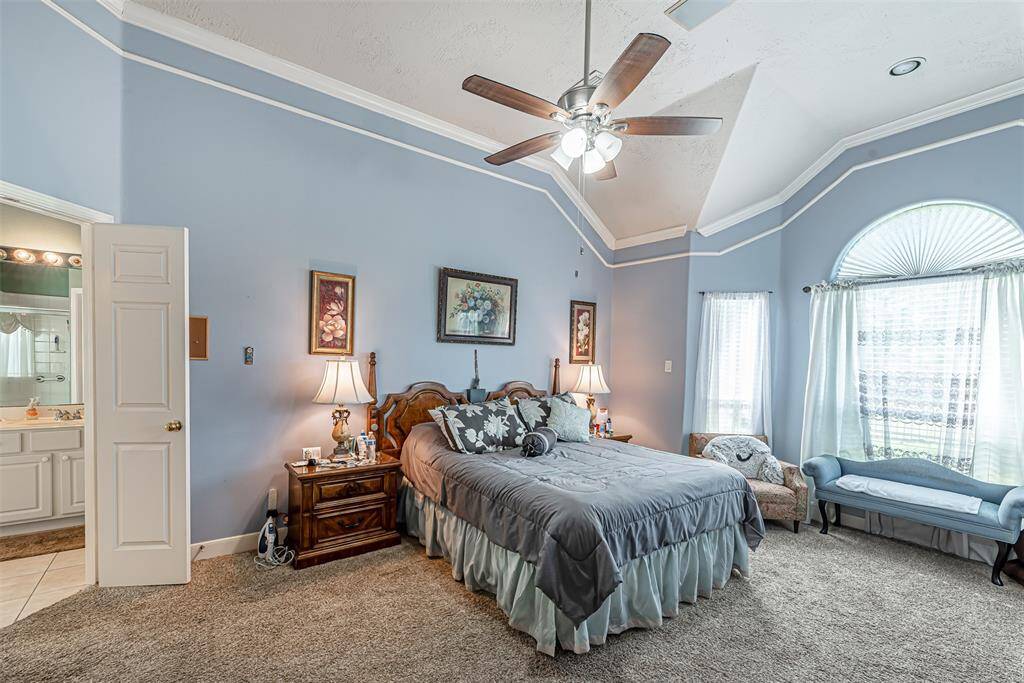 Primary bedroom features crown molding, decorative trim and ceiling fan.