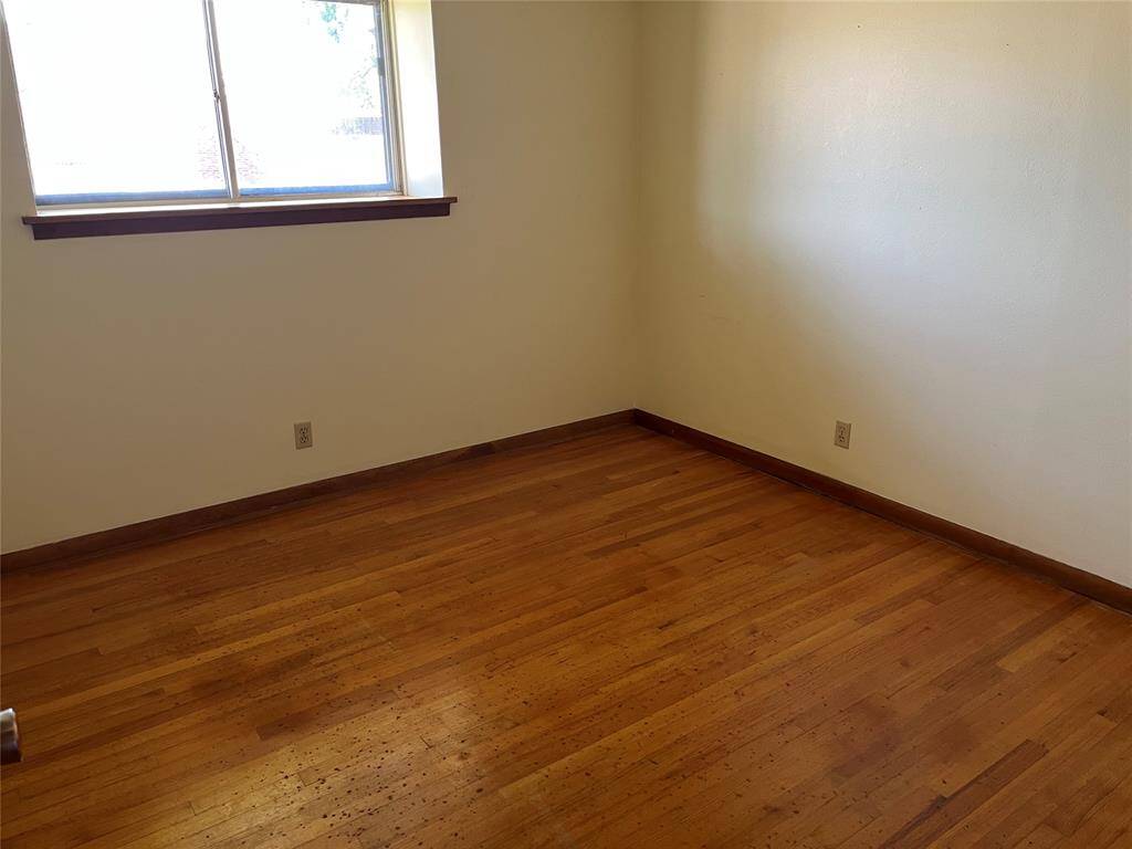 This is the first bedroom. It's along the front of the house, on the right side of the hall as we tour the bedrooms. The little spots are from old carpet pad residue and should come off when the floors are refinished.