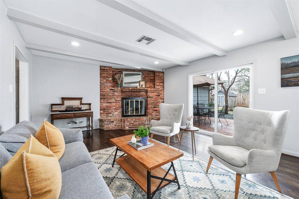 The formal living features a cozy brick faced fireplace and sliding glass door access to the back patio.