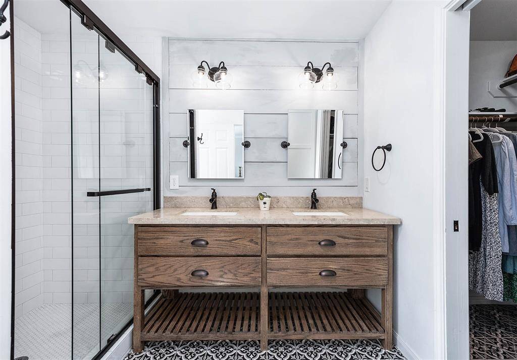This primary bathroom is chic with a walk-in closet to the right.
