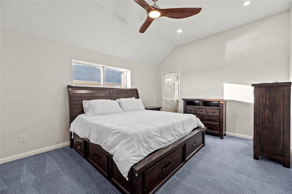 Comfortable upstairs secondary bedroom featuring a modern ceiling fan, plush carpeting, and convenient access to an ensuite bathroom, offering both privacy and practicality.
