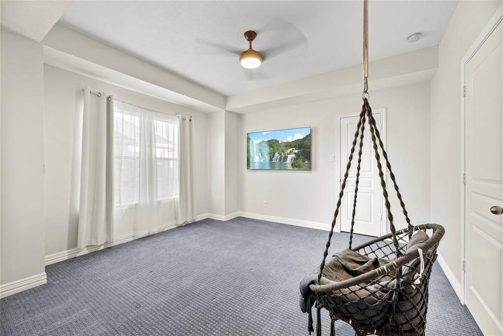 Bright and airy upstairs bedroom featuring soft carpeting, a contemporary ceiling fan, and large windows for natural light.