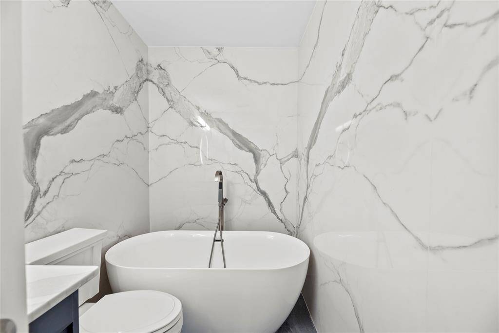Luxurious freestanding soaking tub, surrounded by marble-inspired walls with bold veining.