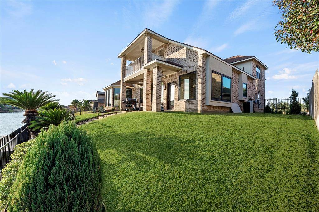 Beautifully landscaped backyard, covered patio, and an upper balcony.